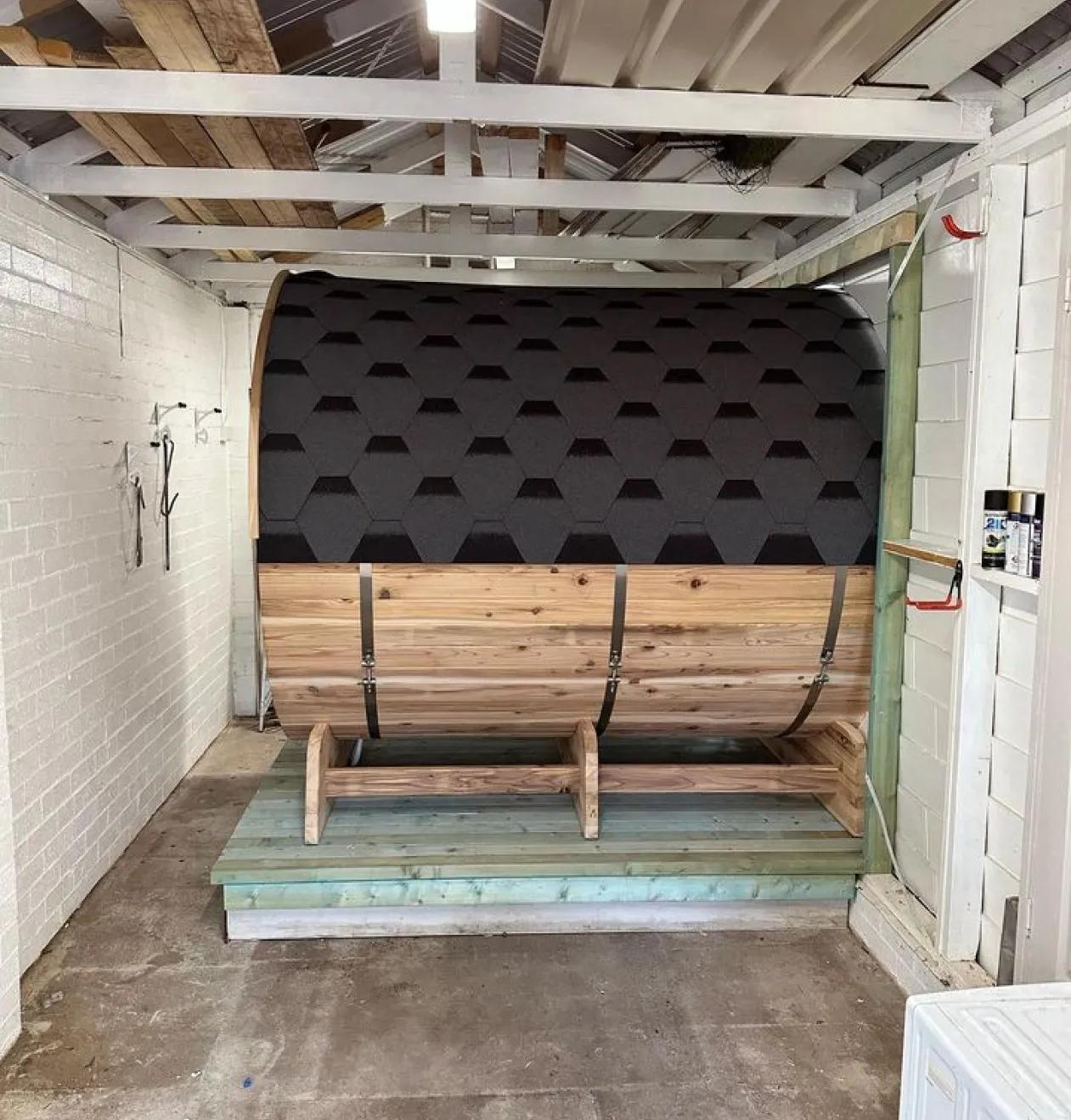 Outdoor barrel sauna installation in a wooden cabin at a residential property